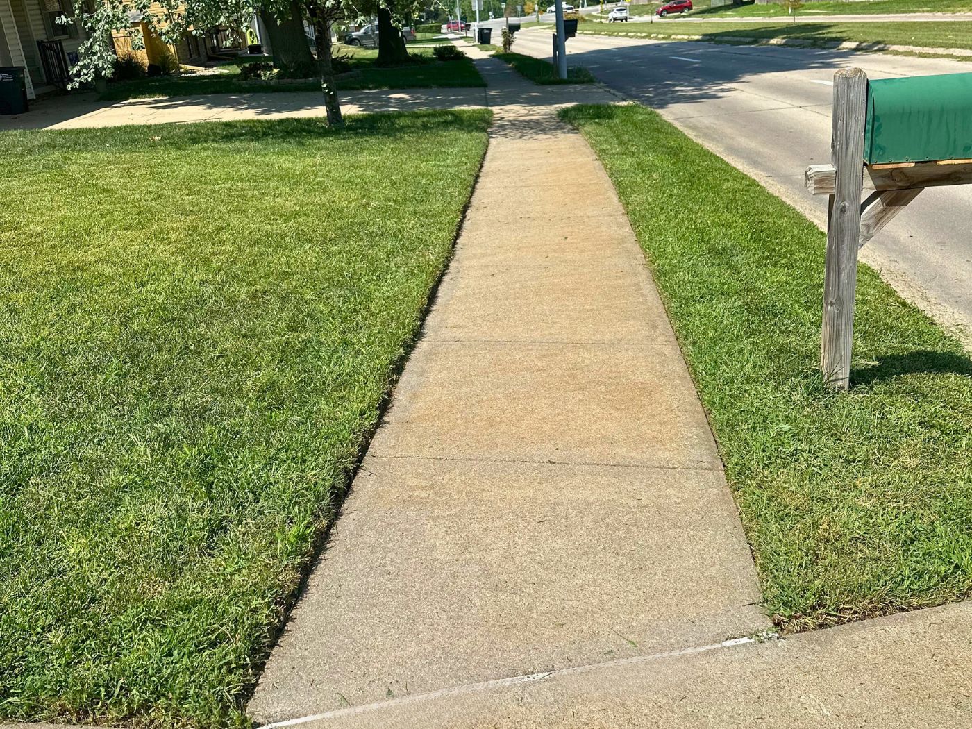 Image of a sidewalk with the grass cut and neatly edged on both sides.